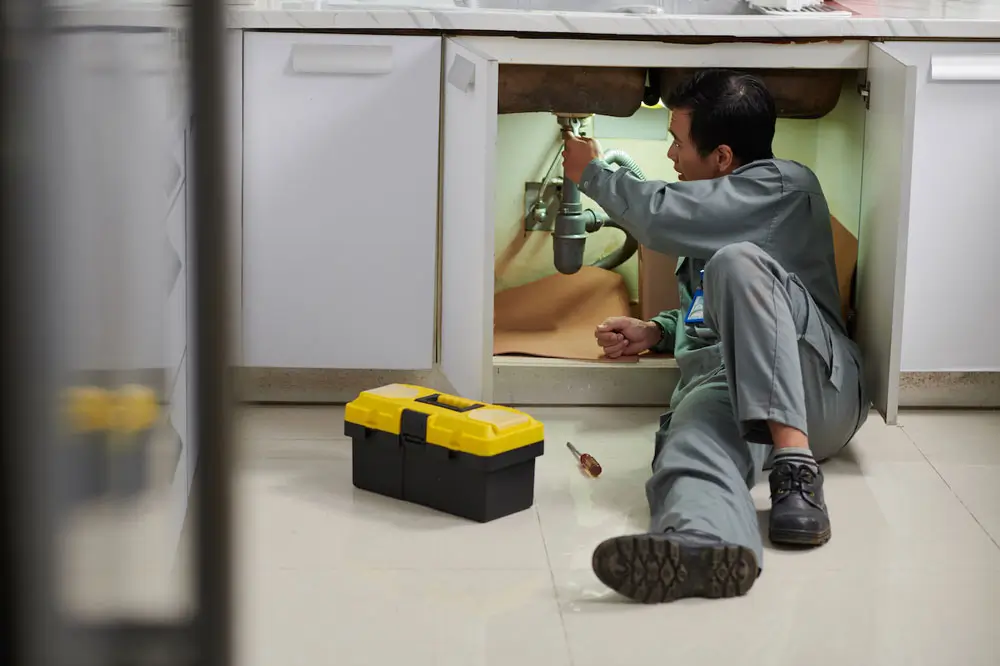 Plumber working under kitchen sink
