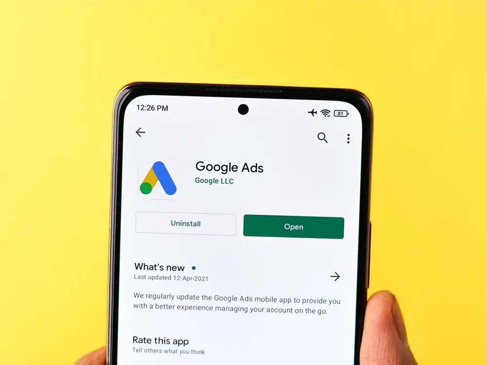 A successful Google Ads specialist uses a laptop to analyze data and optimize campaigns, surrounded by charts and graphs
